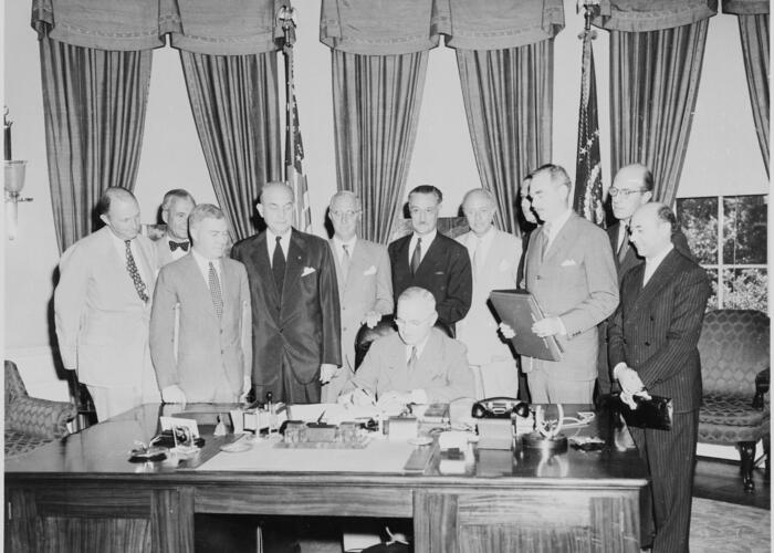 Black and white photograph of men signing NATO treaty in White House