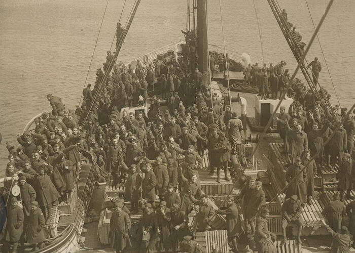 Sepia tone image of group of men standing on board a ship in military uniforms
