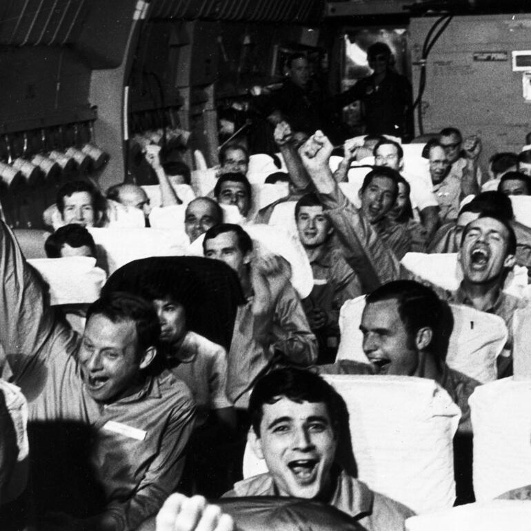 Excited soldiers on a plane lifting their hands in the air