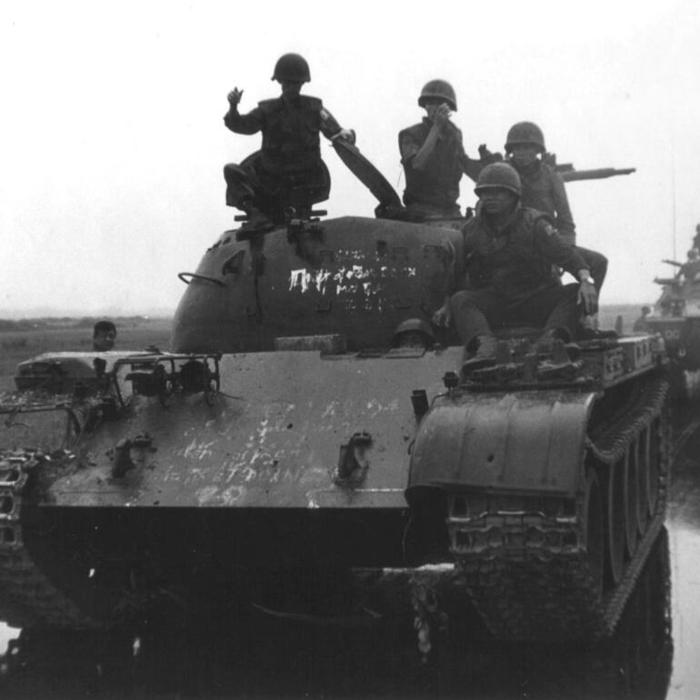 Black and white photograph of soldiers on a tank in the field