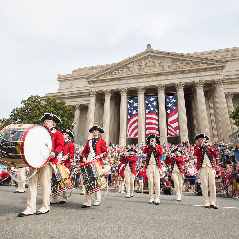 Color photograph of band in revolutionary war uniforms playing in front of the National Archives building
