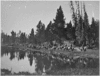 Black and white photograph of a group of men on horseback in front of a body of water.