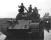 Black and white photograph of soldiers on a tank in the field