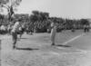 Black and white photograph of women playing baseball with crowd behind.