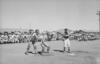 Black and white image of three men playing baseball with a crowd behind.