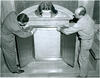 Two men placing document inside of exhibit case
