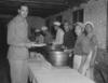 Black and white photograph of men serving food in kitchen