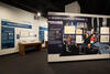 Color photograph of exhibit gallery with image of exhibit case and president in limousine