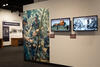 Color photograph of exhibit gallery with case, images, and video screens