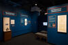 Color photograph of exhibit gallery with cases, text labels, and benches