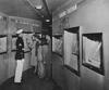 Black and white photograph of visitors looking at an exhibit on the Freedom Train with a Marine standing guard.