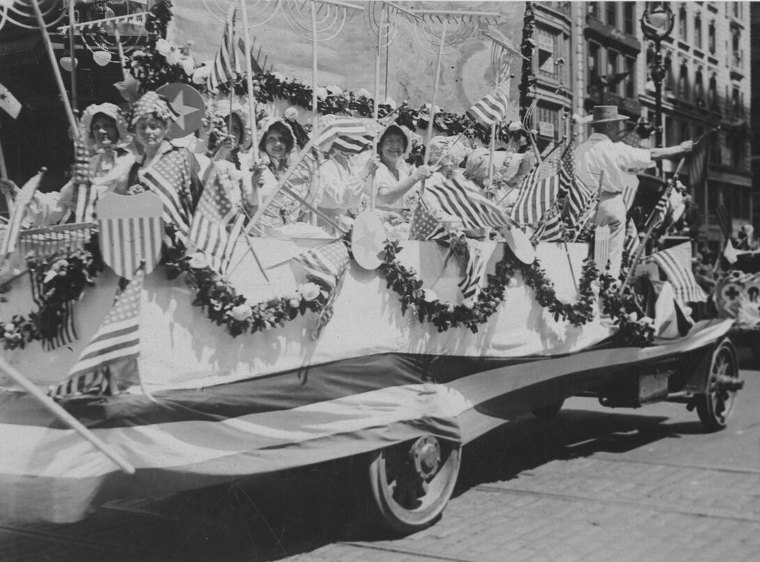 Women riding on a float covered with flags and bunting