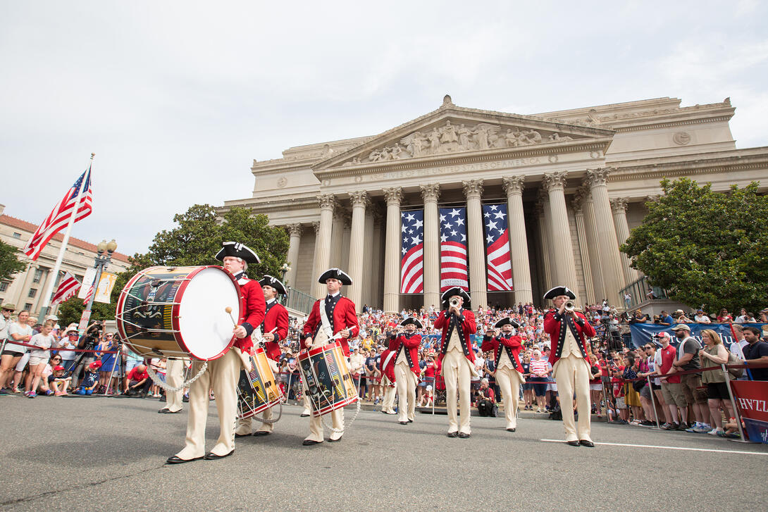 Color photograph of band in revolutionary war uniforms playing in front of the National Archives building