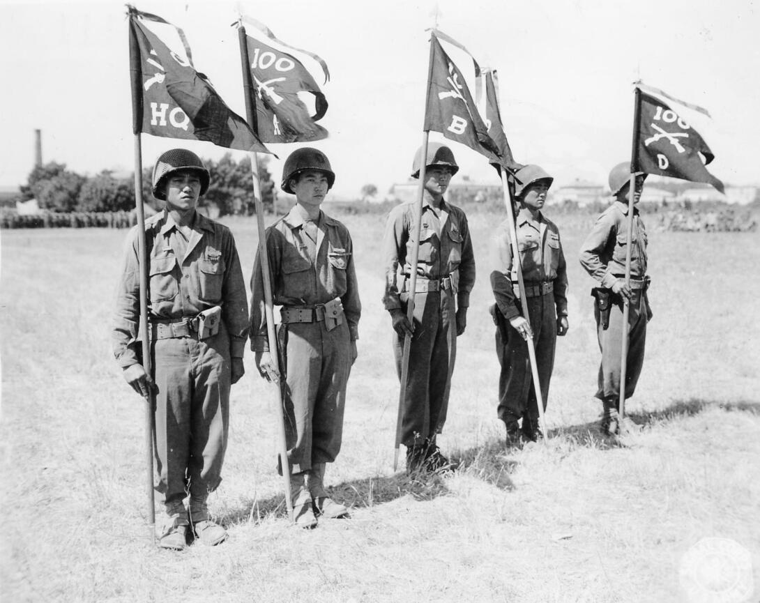 Black and white photograph of five soldiers standing in a field holding battle streamers