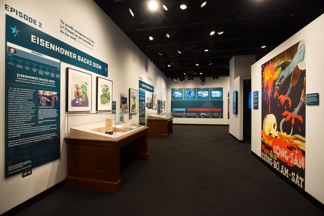 Color photograph of exhibit gallery with exhibit cases on left and imagery on right